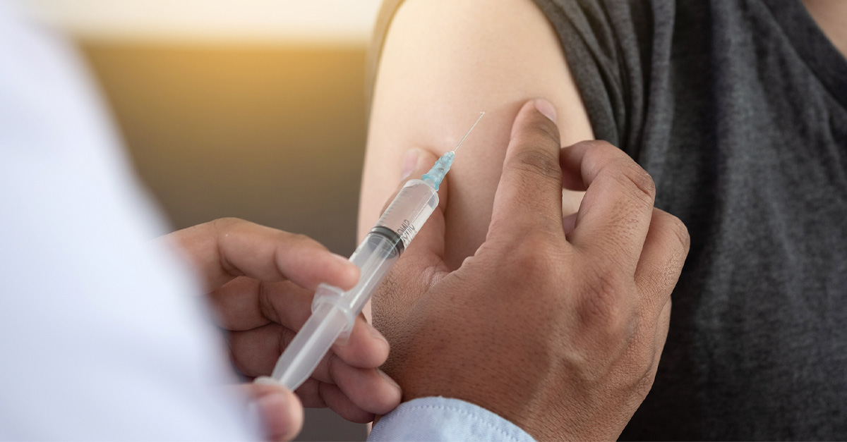 Young adult receiving flu shot from doctor.