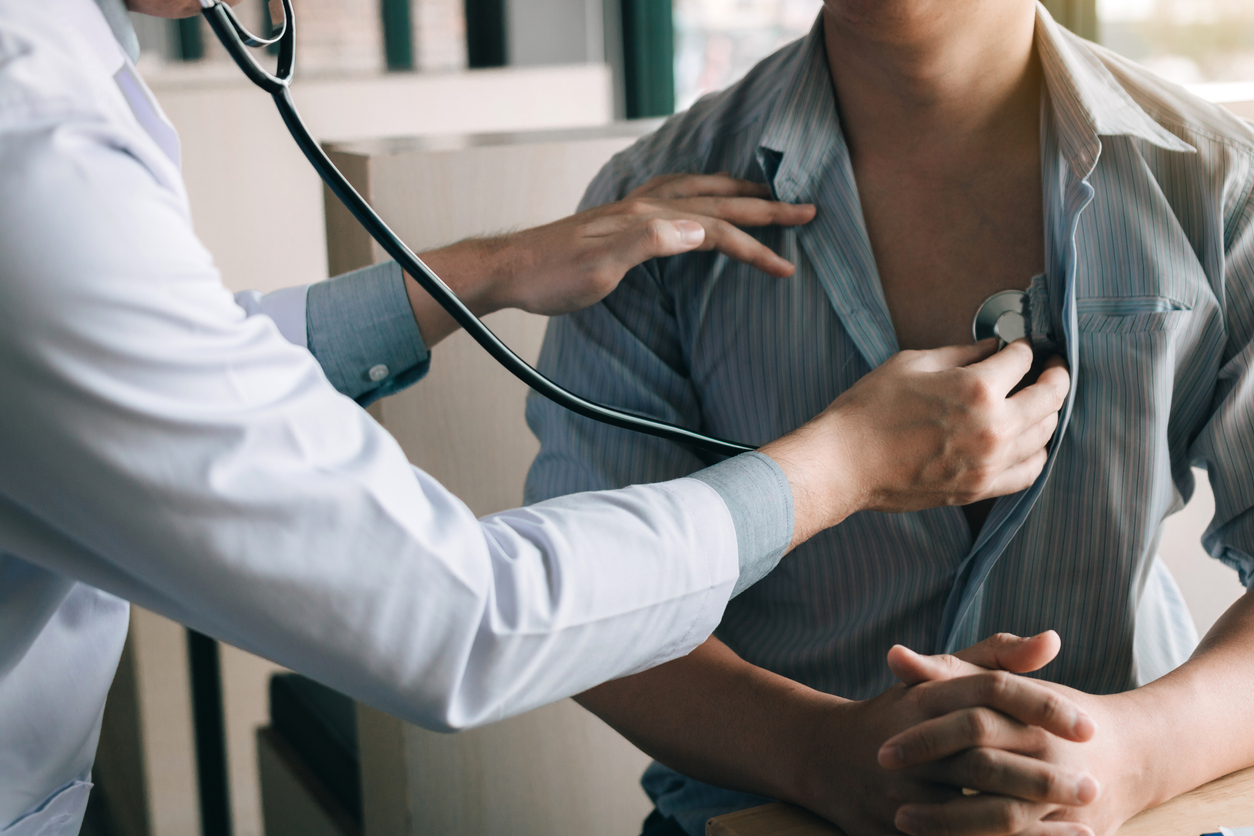 Asian doctor is using a stethoscope listen to the heartbeat of the elderly patient, discussing cholesterol.