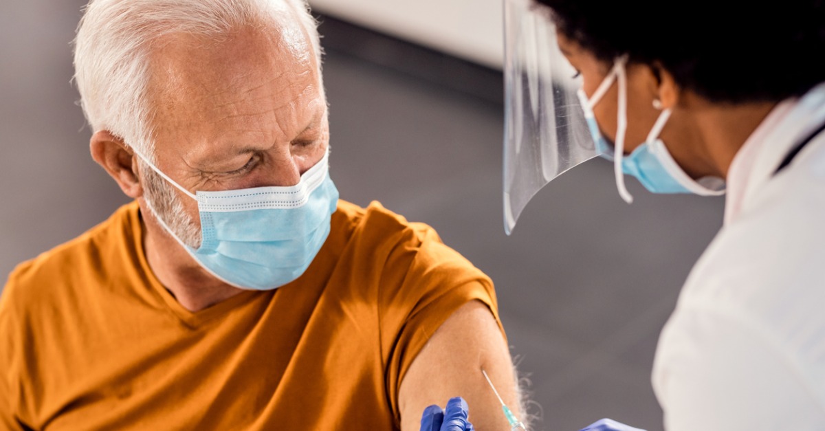 Senior male receiving vaccine while wearing a face mask.