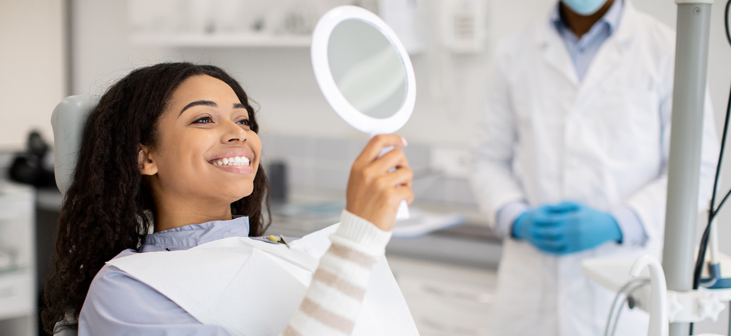 Patient smiling looking at her white teeth at her dentist appointment.