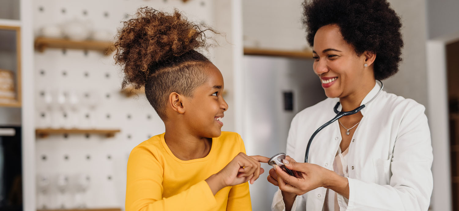 Pediatric patient smiling at her doctor at her doctor’s appointment.