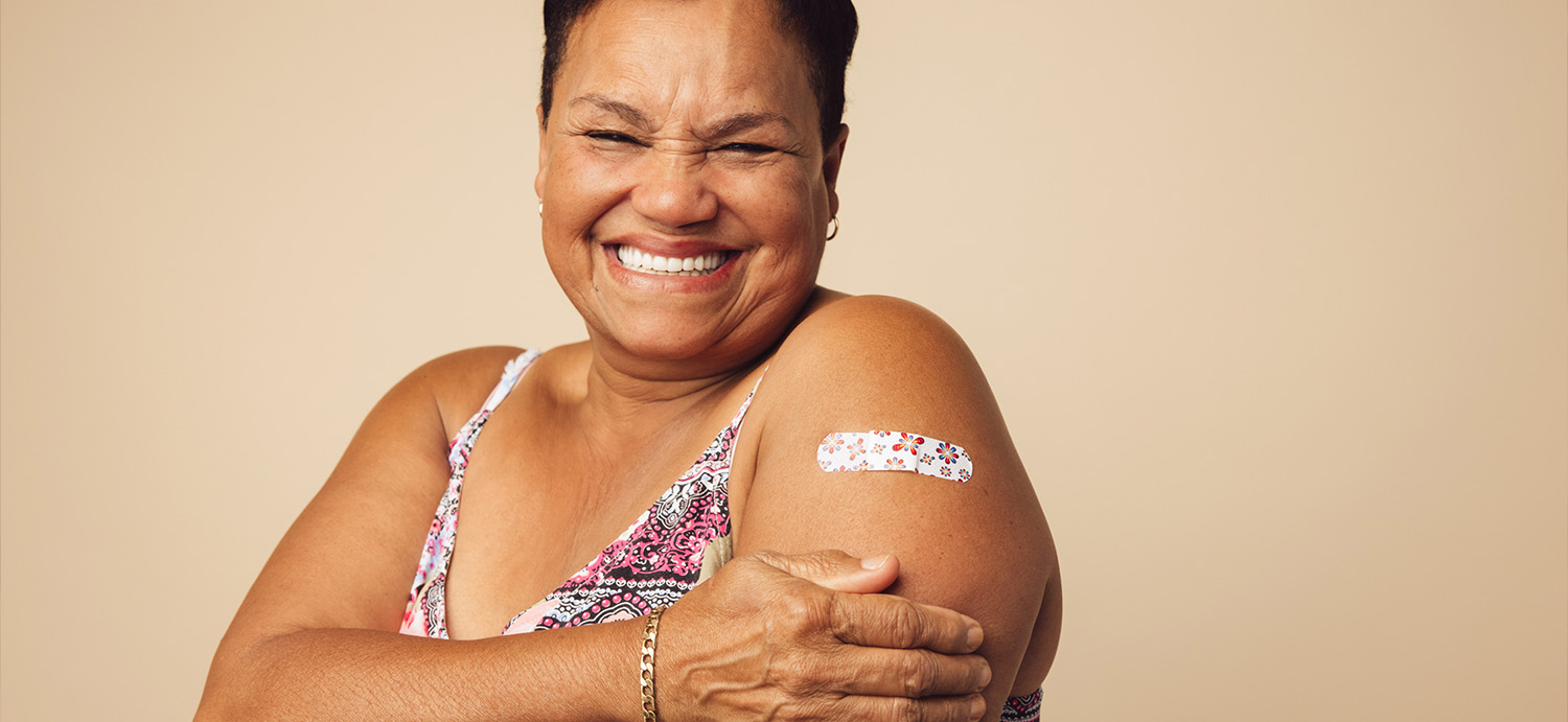 Lady smiling after receiving a vaccine injection in her arm.