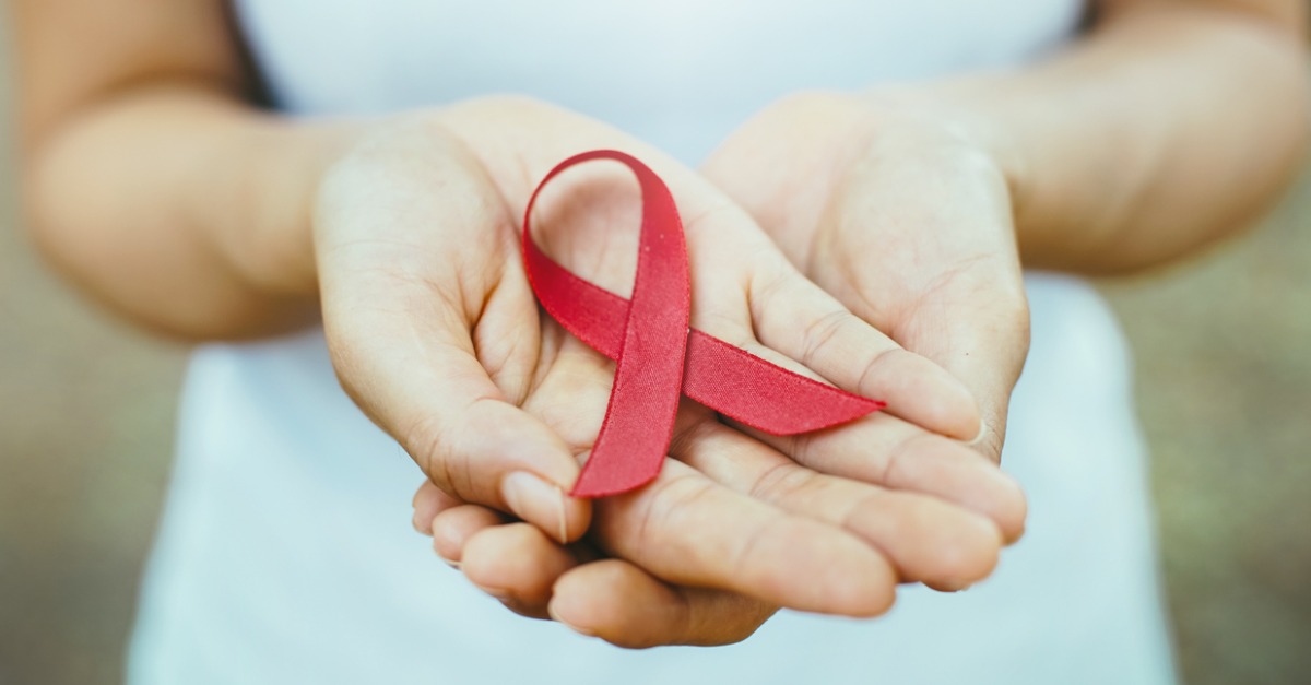 Lady holding red ribbon, representing HIV awareness.