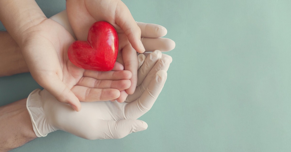 Doctor hands with gloves and child holding red heart