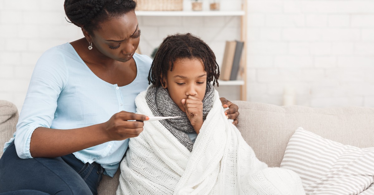 Mother measuring temperature of her sick daughter